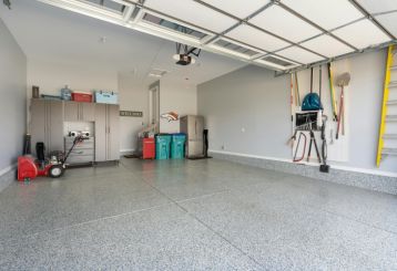 Modern Chanhassen garage featuring custom cabinets, slatwall storage, and overhead racks for organized, clutter-free space.
