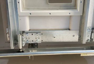 Professional garage door technician repairing a residential garage door with specialized tools in Chanhassen.