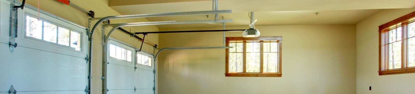 Garage door technician inspecting and repairing a garage door opener system in a residential Chanhassen home.
